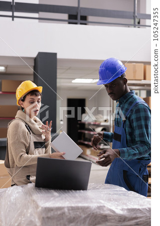 Storehouse managers reading order goods checklist on laptop, choosing cardboard box for packing in warehouse. Man and woman ecommerce store stockroom workers preparing parcel for shipping Storehouse managers reading order goods checklist on laptop, choosing cardboard box for packing in warehouse. Man and woman ecommerce store stockroom workers preparing parcel for shipping 105247355