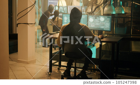 Silhouette of hacker coding encryption to plant trojan virus, looking to steal important information at night. Male thief using computer malware to hack online web network system. Silhouette of hacker coding encryption to plant trojan virus, looking to steal important information at night. Male thief using computer malware to hack online web network system. 105247398