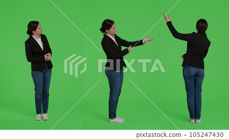 Caucasian businesswoman advertising presentation sideways, doing advertisement over full body greenscreen backdrop. Office worker showing ad icon and example in studio, presenting. 105247430
