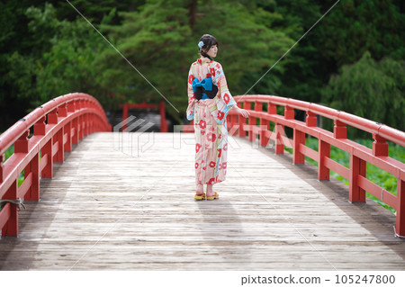 一位穿著浴衣穿過紅橋的美女的後視圖 一位穿著浴衣穿過紅橋的美女的後視圖 105247800