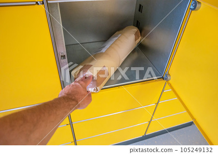 Automatic yellow self pickup and delivery packstation at the post office with opened container and package inside in Germany 105249132