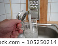 Filling a glass with tap water for drinking by holding it in man hand at the sink in the kitchen 105250214