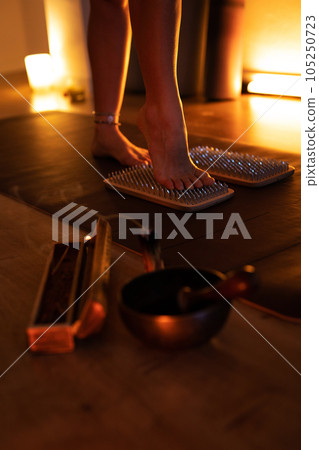 Women's feet stepping on sharp nails for meditation, sadhu wooden board. Yoga practice 105250723