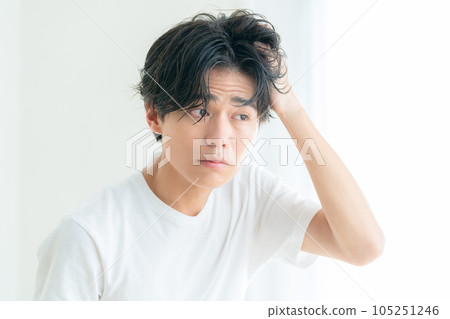 一個年輕人在客廳的窗邊做頭髮護理 105251246