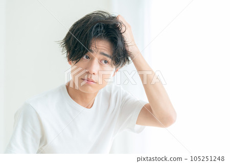 一個年輕人在客廳的窗邊做頭髮護理 105251248