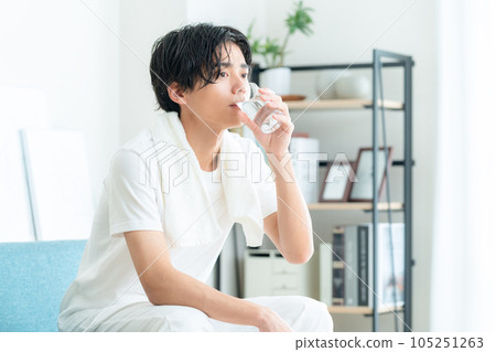 A young man drinking water after taking a bath in the living room 105251263