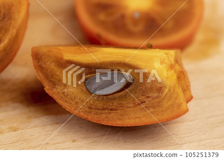 slices of sliced persimmon on a cutting board 105251379