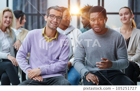 Young people enjoying spending time together on special group therapy. Handsome joyful guy talking jokes and making fun. Young people enjoying spending time together on special group therapy. Handsome joyful guy talking jokes and making fun. 105251727