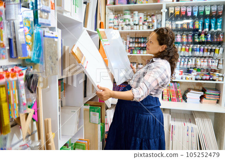 Pregnant female artist standing in the art department of a school stationery store with canvases in her hands Pregnant female artist standing in the art department of a school stationery store with canvases in her hands 105252479