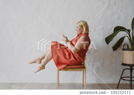 Cheerful woman sitting in armchair and using device. 105252511