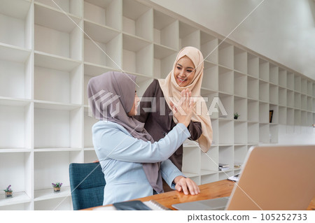 Two hijab Asian women clapping hands together as congratulation after successfully working together. Management concept runs the company female leaders to grow company Two hijab Asian women clapping hands together as congratulation after successfully working together. Management concept runs the company female leaders to grow company 105252733