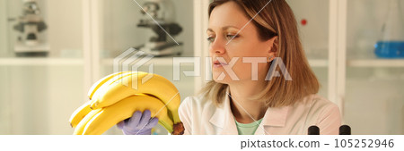 A woman sitting in the laboratory looks at bananas A woman sitting in the laboratory looks at bananas 105252946
