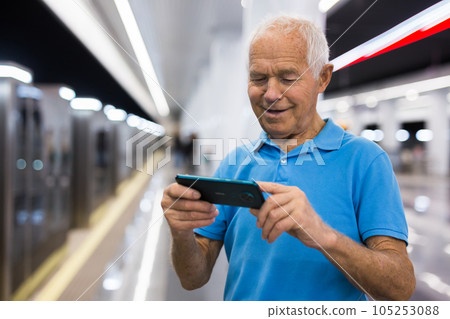 Senior man writing message on smartphone screen in subway 105253088