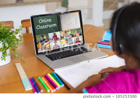 Biracial girl wearing headphones and attending online class over video call on laptop at home Biracial girl wearing headphones and attending online class over video call on laptop at home 105253300