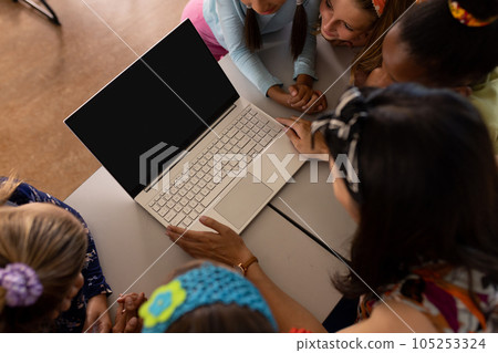 High angle view of diverse female teacher and girls looking at laptop while studying online on table 105253324