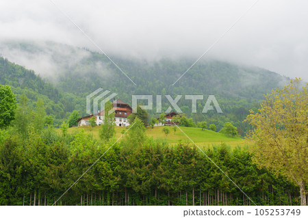 Wooden houses on the hillside. Clouds at the top of the mountain. Wooden houses on the hillside. Clouds at the top of the mountain. 105253749