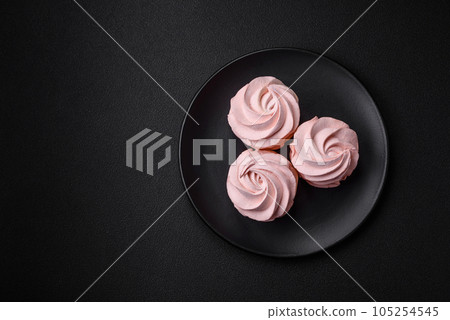 Delicious sweet colored marshmallow on a dark concrete background Delicious sweet colored marshmallow on a dark concrete background 105254545