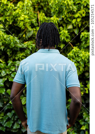 Rear view of african american man with dreadlocks wearing pale blue polo shirt in garden 105254571