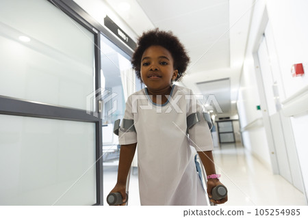 Portrait of african american girl patient walking with crutches in corridor at hospital Portrait of african american girl patient walking with crutches in corridor at hospital 105254985