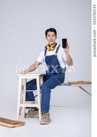 millennials and gen z, korean asian young man carpenter with a smartphone millennials and gen z, korean asian young man carpenter with a smartphone 105256535