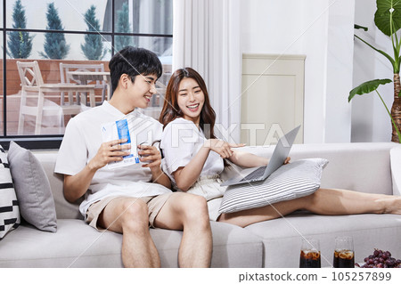 summer lifestyle, korean asian young couple sitting on couch with laptop 105257899
