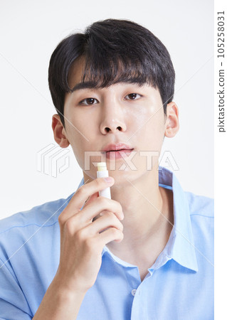 korean asian young man applying lip balm korean asian young man applying lip balm 105258031