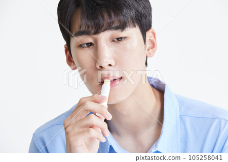 korean asian young man applying lip balm 105258041