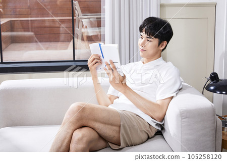 summer lifestyle, korean asian young man reading on couch 105258120
