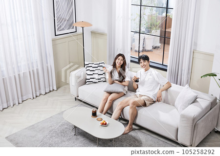summer lifestyle, korean asian young couple sitting on couch with snack 105258292