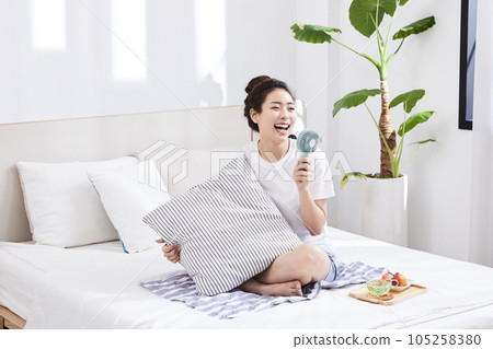 summer lifestyle, korean asian young woman holding a cushion on top of the bed summer lifestyle, korean asian young woman holding a cushion on top of the bed 105258380