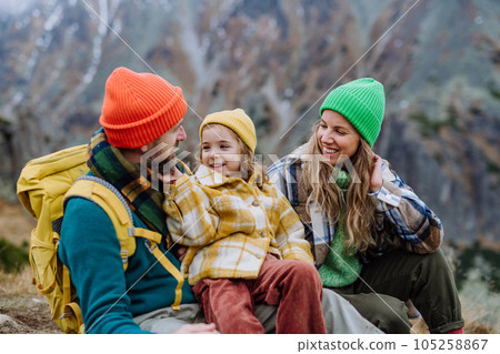 Happy family resting, having snack during hiking together in autumn mountains. 105258867