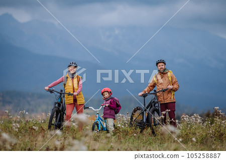 Young family with little daughter at bicycles, in the middle of autumn nature. 105258887