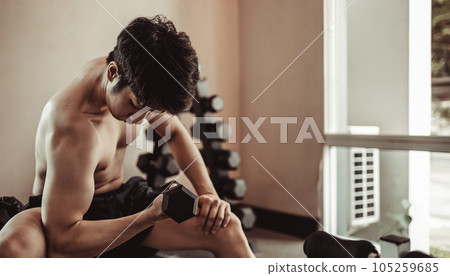 Muscular Young Man Exercising with Dumbbells in Gym - Strength Training and Fitness Concept, Active Gym Workout, Fitness and Determination. 105259685