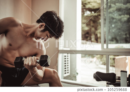 Muscular Young Man Exercising with Dumbbells in Gym - Strength Training and Fitness Concept, Active Gym Workout, Fitness and Determination. 105259688