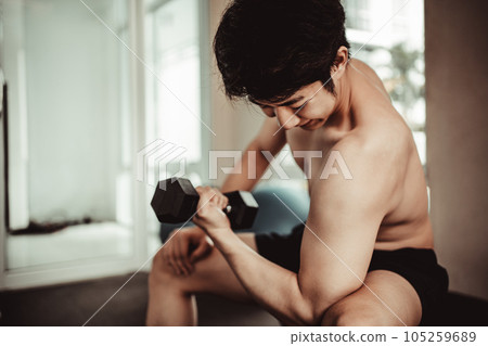 Muscular Young Man Exercising with Dumbbells in Gym - Strength Training and Fitness Concept, Active Gym Workout, Fitness and Determination. 105259689