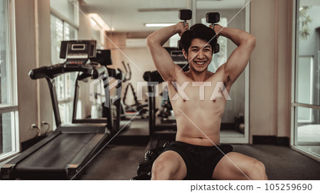 Muscular Young Man Exercising with Dumbbells in Gym - Strength Training and Fitness Concept, Active Gym Workout, Fitness and Determination. 105259690