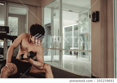 Muscular Young Man Exercising with Dumbbells in Gym - Strength Training and Fitness Concept, Active Gym Workout, Fitness and Determination. 105259691