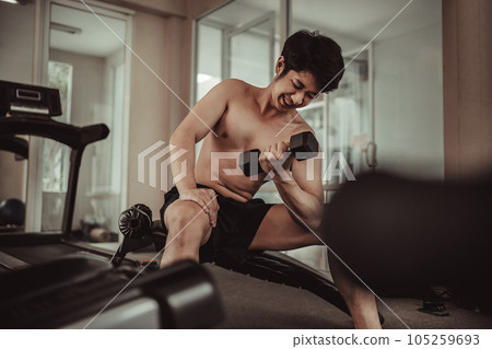 Muscular Young Man Exercising with Dumbbells in Gym - Strength Training and Fitness Concept, Active Gym Workout, Fitness and Determination. 105259693
