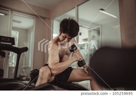 Muscular Young Man Exercising with Dumbbells in Gym - Strength Training and Fitness Concept, Active Gym Workout, Fitness and Determination. Muscular Young Man Exercising with Dumbbells in Gym - Strength Training and Fitness Concept, Active Gym Workout, Fitness and Determination. 105259695