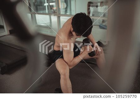 Muscular Young Man Exercising with Dumbbells in Gym - Strength Training and Fitness Concept, Active Gym Workout, Fitness and Determination. 105259770