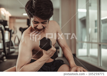 Muscular Young Man Exercising with Dumbbells in Gym - Strength Training and Fitness Concept, Active Gym Workout, Fitness and Determination. 105259771