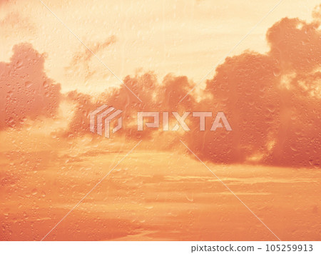 Raindrops on glass window over sunset sky Raindrops on glass window over sunset sky 105259913