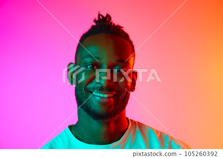 Portrait with smiling african man looking at camera over gradient colorful background in neon. 105260392
