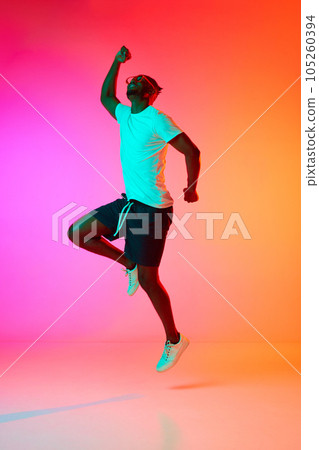 African man in glasses lope happy and laughing over pink-orange background in neon. 105260394