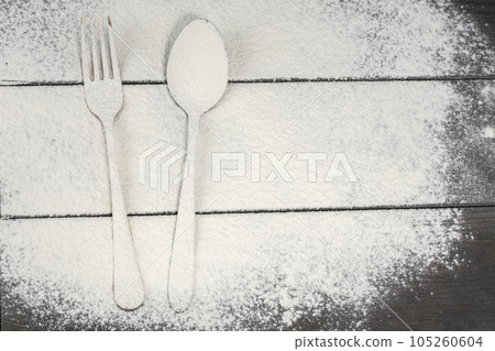 A fork and spoon on a cutting board are sprinkled with flour.Cutlery on the board. A fork and spoon on a cutting board are sprinkled with flour.Cutlery on the board. 105260604