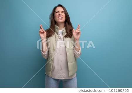 concentrated caucasian young brunette woman in casual clothes hopes on studio background concentrated caucasian young brunette woman in casual clothes hopes on studio background 105260705