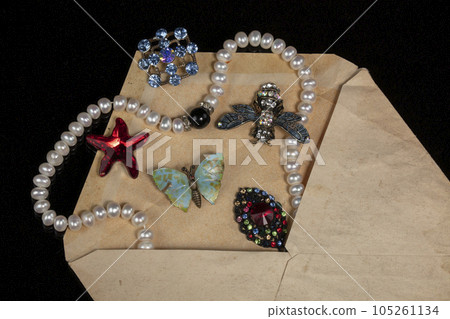 Jewelry, brooches, beads were poured out of an old mail envelope. 105261134