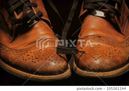A pair of brown vintage leather shoes on a dark background. Beautiful leather shoes. A pair of brown vintage leather shoes on a dark background. Beautiful leather shoes. 105261144