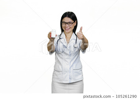 Smiling female doctor with white bottle of pills giving a thumb up. Isolated on white. Smiling female doctor with white bottle of pills giving a thumb up. Isolated on white. 105261290