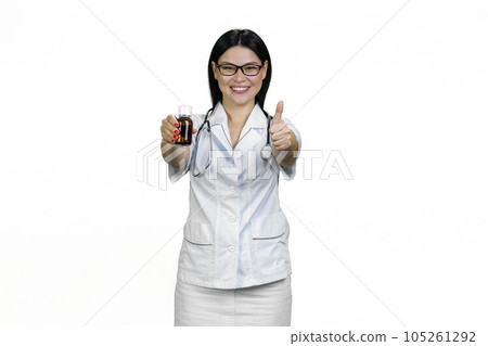 Portrait of asian female smiling doctor with syrup bottle giving a thumb up. Isolated on white. Portrait of asian female smiling doctor with syrup bottle giving a thumb up. Isolated on white. 105261292